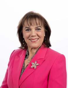 Smiling woman in pink blazer with brooch